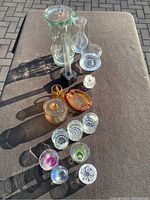 Full lot items arranged on a surface including two vases, amber glassware, faceted knob, and shot glasses.