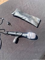 Handheld iRig microphone lying on dark fabric with attached cable and black pouch nearby.