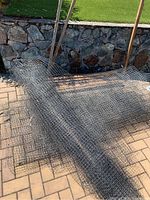 Wooden posts leaning against a wall with rolled metal wire mesh netting on ground
