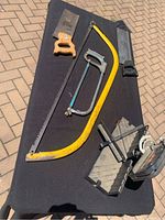 Four saws laid out on black cloth: hand saw, bow saw, hacksaw, and miter box saw.