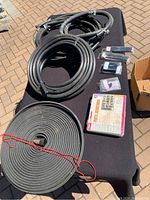 Overview of coiled irrigation tubing, hose sprinkler tubing, and organized parts box with small packages.