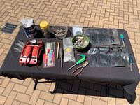 Full layout of items on black cloth showing bike foot pump, screws, tire repair parts, pliers, screwdriver, and plastic tire holders arranged neatly.