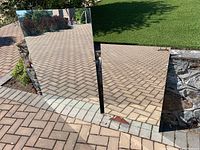 Two rectangular mirrors placed on ground; larger mirror reflects pavement and garden, smaller mirror reflects pavement.