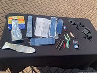 Full lot arranged on black cloth showing paperwork, fishing flashers/dodgers, lures, and mounting hardware.