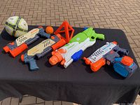 Full lot displayed on a black cloth on pavement. Four water shooters, soccer ball, baseball, and cone clearly shown for identification.