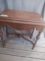 Front view of antique wooden table showing carved apron and turned legs.