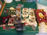Photo showing multiple small bird nests with birds, packaged bird ornaments, ribbon spools, and a decorative wooden sled on a table.