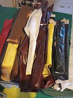 Assorted tanned deer hides and leather pieces laid out showing variety of colors and textures including dark brown, red, yellow, black, tan, and cream.
