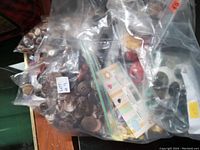 Close-up photo showing several clear plastic bags filled with buttons of various shapes and colors placed on a wooden surface