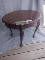 Full view of oval wooden side table showing shape, legs, and overall condition.