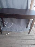 Front view of the dark brown wooden sofa table with drawer and power bar attached at the back.