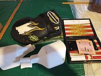 Black catcher's mitt, white hand guards, and open backgammon set visible on green surface.