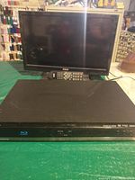 Magnavox Blu-ray/DVD player, black slim unit with disc slot and control buttons on front panel with Blu-ray logo
