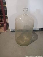 Full view of the large clear glass wine carboy with narrow neck and rounded body.