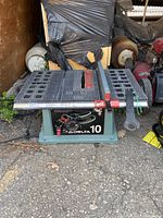 Front view of a Delta 10-inch table saw with metal tabletop, adjustment controls, red blade guard, and attached wrench.