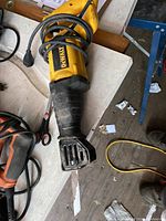 DeWalt reciprocating saw placed on a workbench showing handle, vented blade housing, and wrapped power cord.