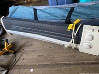 White and black Honeywell electric heater on wooden surface with control panel and power cord visible