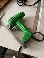 Photo of green electric staple tool branded 'Fast' with metal staple base and attached cord