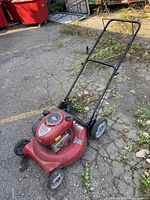 Full view of red Craftsman gas lawn mower showing overall condition and structure with handle and wheels outdoors on pavement