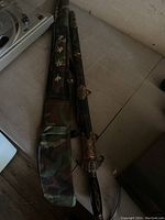 Japanese style sword alongside ornate sheath and camouflage carrying case with Japanese characters