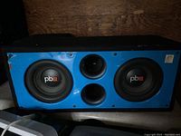 Large rectangular speaker with blue front panel, black enclosure, and two visible woofers with pb logos.