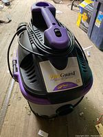 Photo of ProTeam ProGuard portable wet/dry vacuum cleaner with power cord wrapped around the handle, showing front and top of the unit.