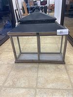 Front view of a rectangular glass display case with metal frame and decorative top vent with finial.