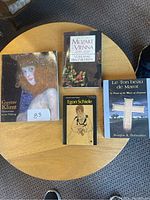 Photo of four books on a round wooden table: Gustav Klimt, Mozart in Vienna, Egon Schiele, Le Ton Beau de Marot