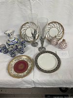 Photo of assorted ceramic and porcelain items including plates, decorative pieces, glassware, and sangria pitcher with cups.
