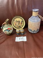 Full assortment of ceramic items displayed together including pitcher, plate, bottle, and salt and pepper shakers.