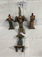 Front view of the set of four small Mexican clay statuettes arranged in a group on a white cloth background, showing detail and color variation.