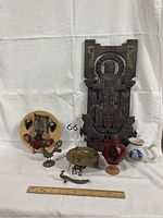 Photo of assorted decorative items including carved wooden wall hanging, pottery plates, brass candle holder and figurines.