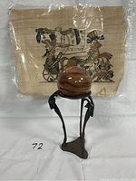 Photo showing two items against a white backdrop: an Egyptian painting on papyrus and a spherical marble globe on a brass stand