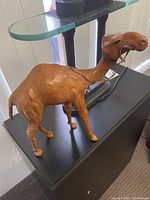 Leather camel figurine decor item on display table showing full side view and leather detailing.
