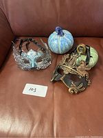 Photo showing two Venetian style masks and two glazed pottery pumpkins on a brown leather background.