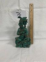 Front view of green Mexican figurine statuette sitting next to a ruler showing height around 12 inches.