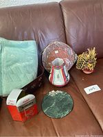 Full view of lot items set on brown leather sofa including textiles, ceramics, and collectibles