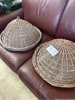 Two round wicker food baskets with domed lids on sofa showing overall appearance of both