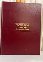 Full image of the front cover of the red hardcover book titled 'Front Page 100 Years of the Los Angeles Times' with gold lettering.