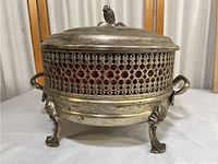 Full side view of the brass Portuguese serving dish showing pierced sides, handles, and claw-foot legs.
