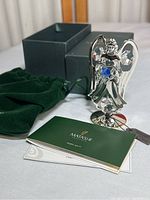 Matashi silver plated angel figurine with box, velvet pouch, and literature laid out on a surface.
