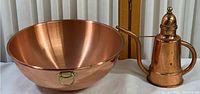 Polished copper bowl and kettle placed next to each other showing overall shape and size.