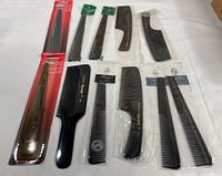 Overview of entire collection showing 10 various professional combs, some in packages and some loose, with black color and varying tooth spacing and handle styles.