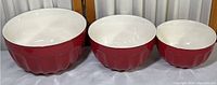 Set of three nesting mixing bowls showing red exterior and white interior