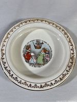 Top down view of the vintage baby plate showing central illustration and gold decorative border.
