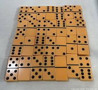 Top-down photo of the 28 beige domino tiles laid out in rows showing their black dot patterns.
