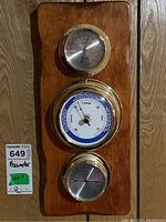 Full view of the wooden base with three mounted weather instruments: thermometer, barometer, and hygrometer/clock dial, showing overall condition and layout.