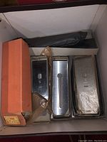Three large metal blades in a box with one orange box and protective sheets