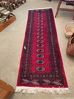 Full view of the Bokhara runner rug on carpeted floor showing the overall design and colors.
