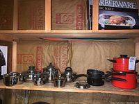 Wide view of 9 cookware items arranged on shelf by brand and type.